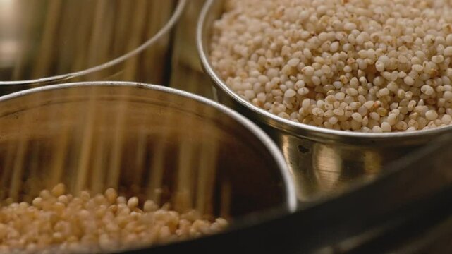 filling barnyard millet in steel bowl with little millet in the background for storage, 4k, close up, stable shot