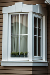 Fototapeta premium Elegant White Bay Window on Brown House Exterior. Beautiful home design, real estate, and home improvement concept. High-quality window frame and glass. Potted plants add a touch of nature.