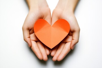 Obraz premium Hands holding a heart-shaped paper cutout against a light background express love and care in a creative and simple way