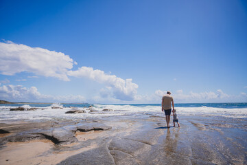 Father and son walk on beach holding hands