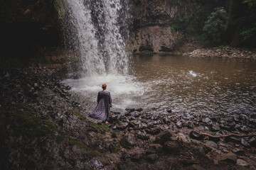 Woman at waterfall with blowing dress
