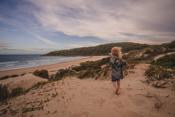 Young boy running down sand dune 