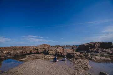 two children playing in rock pools 