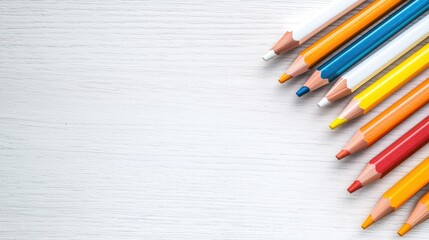 Obraz premium Colorful wooden pencils arranged diagonally on a white wooden table with copy space.