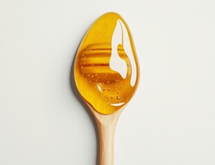 Golden honey dripping from wooden spoon on white.