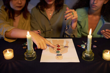 High angle view of three girls placing gemstones onto human design image during energy practice at...