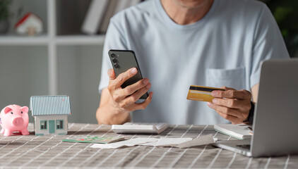 Man shopping online with credit card at home, using smartphone for purchases
