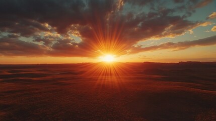 Dramatic sunset over a vast desert landscape with fiery orange and deep cloud patterns