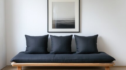 A Minimalist Room Features A Low Wooden Bench With Dark Gray Cushions And A Framed Black And White Seascape Print Above It. The Overall Vibe Is Serene And Calm.