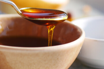 Honey being drizzled from a spoon into a bowl