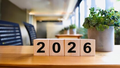 Year Blocks Displaying 2026 on Wooden Table - A cozy indoor setting featuring wooden blocks showing the year 2026 surrounded by green plants and a warm atmosphere.