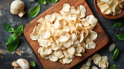 Fototapeta premium Crispy mushroom chips on wooden board, garnished with basil. Perfect for healthy snacking, food blogs, or culinary websites.