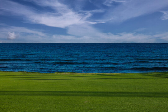 green grass and blue sky and ocean with clouds