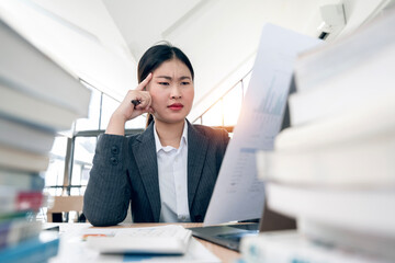 Frustrated business woman working on piles of files in office