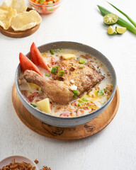 Mouthwatering soto ayam or chicken soup features tender meat, fresh vegetables, and crispy toppings served in a rustic bowl with lime