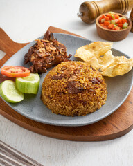 Enjoy a plate of aromatic fried rice served with grilled chicken, fresh cucumber, ripe tomato, and crispy crackers, perfect for a vibrant meal
