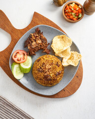 A flavorful dish features rice topped with crispy fried onions, served with cucumber, tomato, snacks, and a fresh vegetable salad for brunch
