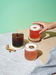 A hand reaches for a vibrant drink on a marble table, featuring an iced coffee, a colorful...