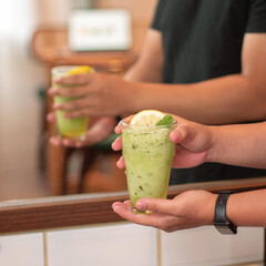 Two friends hold chilled mint lime drinks in a warm, inviting cafe, enjoying leisurely time together in a relaxed atmosphere