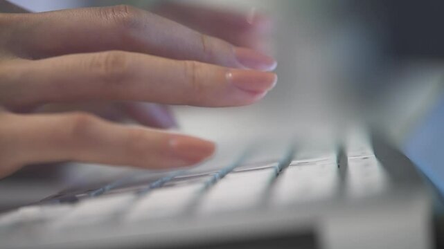 夜景の見える空間でパソコンのキーボードをタイプする手元