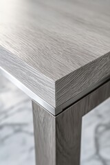 Close-up of a light gray wood table top with a silver metal edge.