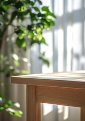Sunlight illuminates a light wood table near a window with sheer curtains and a green plant.