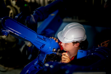 male engineer workers maintenance automatic robotic arm machine in a factory. worker checking and repairing automatic robot hand machine. technician worker check for repair factory machine.