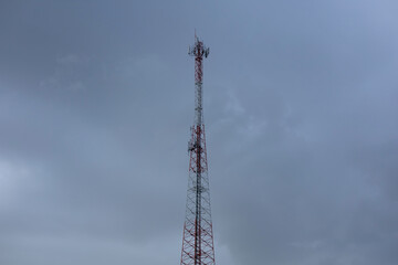 Obraz premium Red and white mobile phone signal tower on a cloudy day