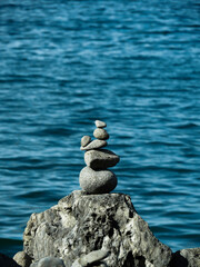 stack of stones balancing in a pile on a rock in front of the ocean. The rocks are smooth and a tranquil form of art in nature