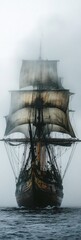 Antique sailing vessel emerges from dense fog on dark water with billowing sails and ornate details