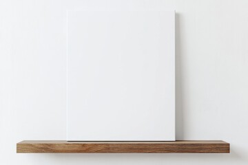 Blank canvas on a wooden shelf against a white wall. Minimalist interior design.