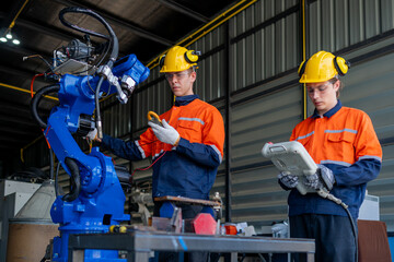 group of male engineer workers maintenance automatic robotic arm machine in a dark room factory. worker checking and repairing automatic robot hand machine. Worker wearing safety glasses and helmet.