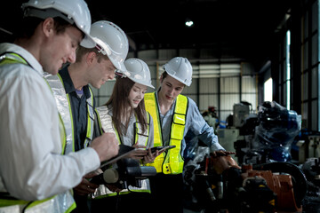 team engineers inspecting on machine with smart tablet. Worker works at heavy machine robot arm. The welding machine with a remote system in an industrial factory. Artificial intelligence concept.