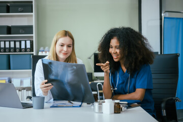 An African American female doctor and a white female doctor work at  hospital desk, discussing patient treatment,medical analysis,healthcare strategies ensure quality medicine effective patient care