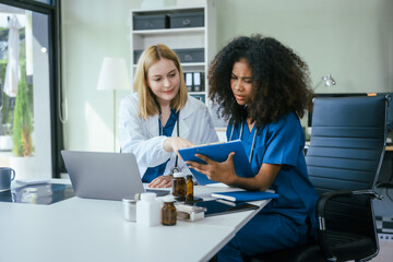 An African American female doctor and a white female doctor work at  hospital desk, discussing patient treatment,medical analysis,healthcare strategies ensure quality medicine effective patient care