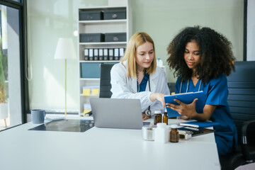 An African American female doctor and a white female doctor work at  hospital desk, discussing patient treatment,medical analysis,healthcare strategies ensure quality medicine effective patient care