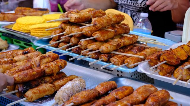 Close-up of Filipino street food featuring caramelized banana fritters on skewers, a vibrant display of local delicacies, ideal for culinary, cultural, or travel-themed footage.