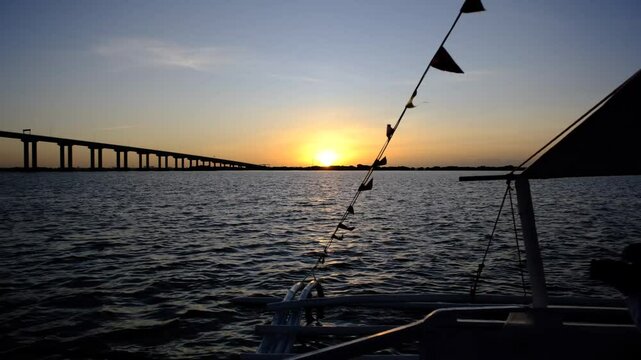 Serene sunset over the water in the Philippines, featuring a silhouette of a boat and a bridge, ideal for travel, nature, and tranquil scenery.
