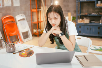 A happy Asian teenage girl painting with a brush on canvas at home, enjoying creativity and relaxation in a cozy, peaceful setting filled with artistic inspiration and vibrant colors