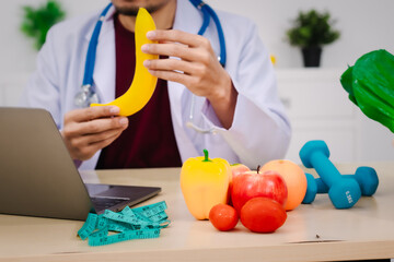 A male nutritionist sitting at a table, advising on healthy diets, promoting vegetable-based meals,...