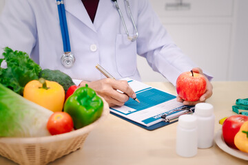 A male nutritionist sitting at a table, advising on healthy diets, promoting vegetable-based meals,...