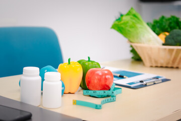 A nutritionist's table with a vegetable basket, fruits, pill bottles, and a dumbbell, symbolizing health, balanced nutrition, fitness, supplements, and a commitment to a healthy lifestyle