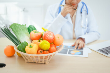 An Asian female doctor at her hospital desk works on a laptop, discussing the importance of eating...