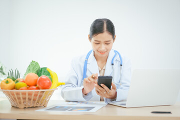 An Asian female doctor at her hospital desk works on a laptop, discussing the importance of eating...