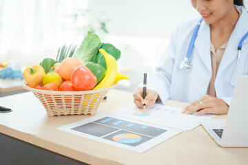 An Asian female doctor at her hospital desk works on a laptop, discussing the importance of eating...