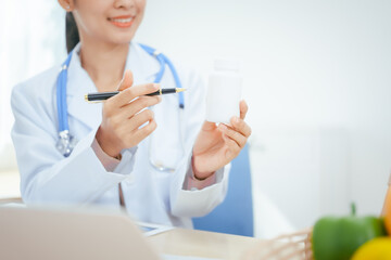 A young female nutritionist expert works at a hospital desk,consulting female patients about eating...