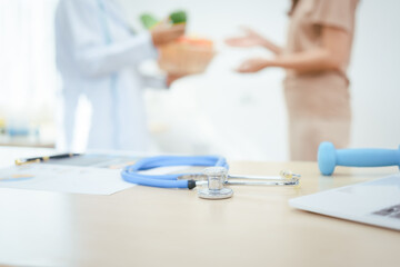 A young female nutritionist expert works at a hospital desk,consulting female patients about eating vegetables fruits, promoting a healthy diet,providing guidance for effective weight loss wellness