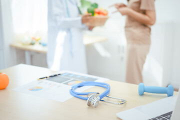 A young female nutritionist expert works at a hospital desk,consulting female patients about eating vegetables fruits, promoting a healthy diet,providing guidance for effective weight loss wellness