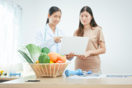 A young female nutritionist expert works at a hospital desk,consulting female patients about eating vegetables fruits, promoting a healthy diet,providing guidance for effective weight loss wellness
