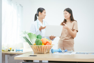 A young female nutritionist expert works at a hospital desk,consulting female patients about eating vegetables fruits, promoting a healthy diet,providing guidance for effective weight loss wellness